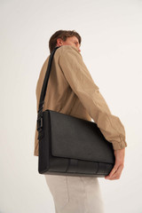 Profile view of model wearing the Oroton Eton Satchel in Black and Saffiano/Smooth Leather for Men