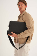 Profile view of model wearing the Oroton Eton Satchel in Black and Saffiano/Smooth Leather for Men