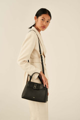 Profile view of model wearing the Oroton Avery Small Three Pocket Day Bag in Black and Soft Pebble Leather for Women