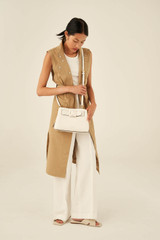 Profile view of model wearing the Oroton Avery Small Three Pocket Day Bag in Cream and Soft Pebble Leather for Women