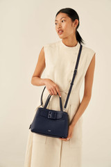 Profile view of model wearing the Oroton Avery Small Three Pocket Day Bag in Denim Blue and Soft Pebble Leather for Women