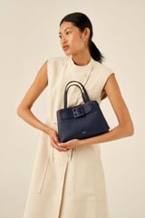 Profile view of model wearing the Oroton Avery Small Three Pocket Day Bag in Denim Blue and Soft Pebble Leather for Women
