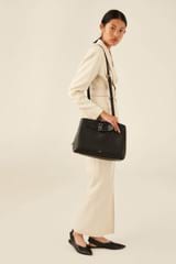 Profile view of model wearing the Oroton Avery Three Pocket Day Bag in Black and Soft Pebble Leather for Women