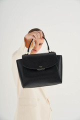 Profile view of model wearing the Oroton Inez Medium Satchel in Black and Shiny Soft Saffiano for Women