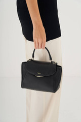 Profile view of model wearing the Oroton Inez Small Satchel in Black and Shiny Soft Saffiano for Women