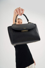 Profile view of model wearing the Oroton Inez Small Satchel in Black and Shiny Soft Saffiano for Women