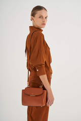 Profile view of model wearing the Oroton Inez Small Satchel in Cognac and Shiny Soft Saffiano for Women