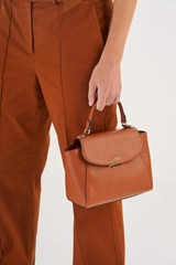 Profile view of model wearing the Oroton Inez Small Satchel in Cognac and Shiny Soft Saffiano for Women