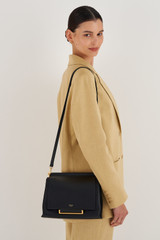 Profile view of model wearing the Oroton Elm Medium Day Bag in Black and Pebble leather with smooth leather trims for Women