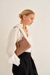 Profile view of model wearing the Oroton Dylan Baguette in Tan and Pebble Leather for Women