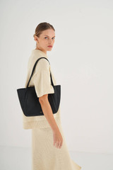 Profile view of model wearing the Oroton Dylan Small Tote in Black and Pebble Leather for Women