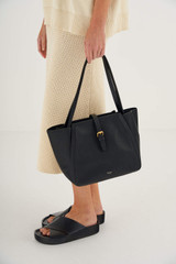 Profile view of model wearing the Oroton Dylan Small Tote in Black and Pebble Leather for Women