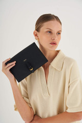 Profile view of model wearing the Oroton Dylan Fold Over Crossbody in Black and Pebble Leather for Women