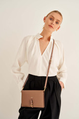 Profile view of model wearing the Oroton Dylan Fold Over Crossbody in Tan and Pebble Leather for Women