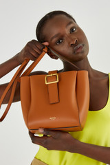 Profile view of model wearing the Oroton Ingrid Bucket in Brandy and Smooth Leather for Women