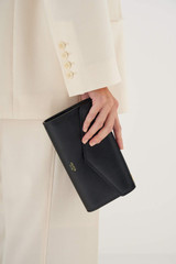 Profile view of model wearing the Oroton Bella Clutch Wallet in Black and Soft Saffiano for Women