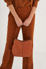 Profile view of model wearing the Oroton Kali Small Hobo in Cognac and Pebble leather for Women