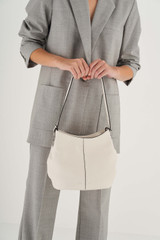 Profile view of model wearing the Oroton Kali Medium Hobo in Cream and Pebble leather for Women