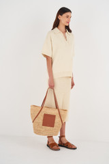 Profile view of model wearing the Oroton Jensen Tote in Natural/Brandy and Smooth Leather and Crocheted Straw for Women