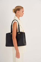 Profile view of model wearing the Oroton Anika 13" Day Bag in Black and Pebble leather for Women