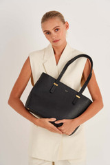 Profile view of model wearing the Oroton Anika 13" Tote & Cover in Black and Pebble leather for Women