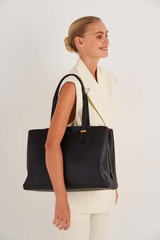 Profile view of model wearing the Oroton Anika 15" Day Bag in Black and Pebble leather for Women