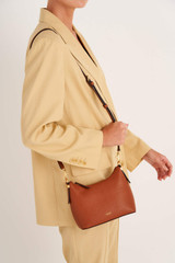 Profile view of model wearing the Oroton Anika Crossbody in Cognac and Pebble leather for Women