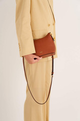 Profile view of model wearing the Oroton Anika Crossbody in Cognac and Pebble leather for Women