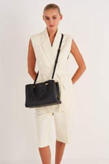 Profile view of model wearing the Oroton Anika Small Day Bag in Black and Pebble leather for Women