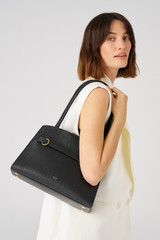 Profile view of model wearing the Oroton Audrey Small Three Pocket Day Bag in Black and Saffiano and Smooth Leather for Women