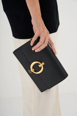 Profile view of model wearing the Oroton Alexa Wallet Clutch in Black and Brass for Women