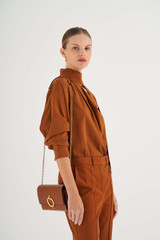 Profile view of model wearing the Oroton Alexa Wallet Clutch in Cognac and Brass for Women