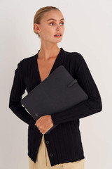 Profile view of model wearing the Oroton Anika 13" Laptop Sleeve in Black and Pebble leather for Women