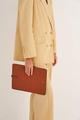 Profile view of model wearing the Oroton Anika 13" Laptop Sleeve in Cognac and Pebble leather for Women
