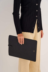 Profile view of model wearing the Oroton Anika 15" Laptop Sleeve in Black and Pebble leather for Women