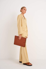 Profile view of model wearing the Oroton Anika 15" Laptop Sleeve in Cognac and Pebble leather for Women