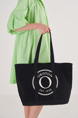 Profile view of model wearing the Oroton Kane Large Shopper Tote in Black and Recycled Canvas for Women