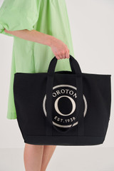 Profile view of model wearing the Oroton Kane Large Shopper Tote in Black and Recycled Canvas for Women