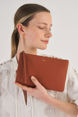 Profile view of model wearing the Oroton Eve Medium Pouch in Cognac and Pebble leather for Women