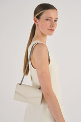 Profile view of model wearing the Oroton Bella Small Clutch in Milk/Matte Silver and Soft Saffiano for Women