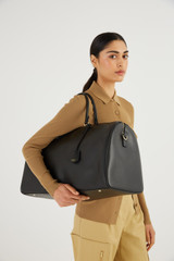 Profile view of model wearing the Oroton Inez Weekender in Black and Saffiano Leather for Women