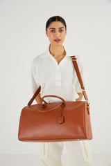 Profile view of model wearing the Oroton Inez Weekender in Cognac and Saffiano Leather for Women