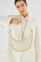 Profile view of model wearing the Oroton Penny Small Shoulder Bag in French Vanilla and Smooth Leather for Women