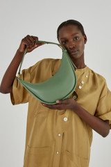 Profile view of model wearing the Oroton Penny Small Shoulder Bag in Shale Green and Smooth Leather for Women