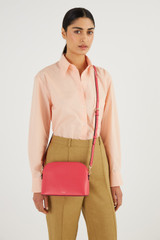 Profile view of model wearing the Oroton Inez Slim Crossbody in Peony Pink and Shiny Soft Saffiano for Women