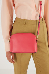 Profile view of model wearing the Oroton Inez Slim Crossbody in Peony Pink and Shiny Soft Saffiano for Women