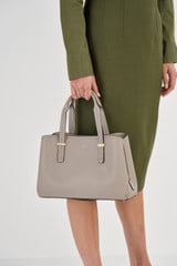 Profile view of model wearing the Oroton Anika Small Day Bag in Oyster and Pebble leather for Women