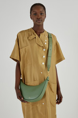 Profile view of model wearing the Oroton Ava Leather Bag Strap in Shale Green and Smooth Leather for Women