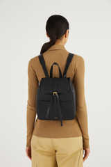 Profile view of model wearing the Oroton Dylan Medium Zip Buckle Backpack in Black and Pebble Leather for Women