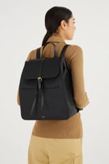 Profile view of model wearing the Oroton Dylan Large Zip Buckle Backpack in Black and Pebble Leather for Women
